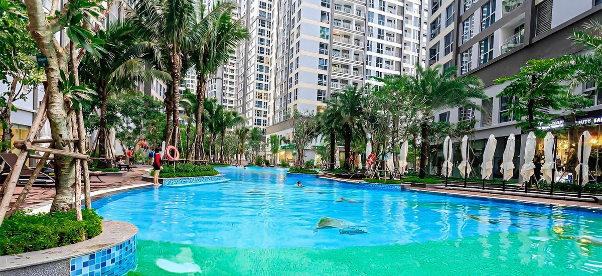 Hồ bơi ngoài trời rợp bóng cọ giữa các tòa tháp